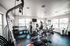 Bright and modern fitness room featuring state-of-the-art equipment, large windows for natural light, and a clean, inviting atmosphere.