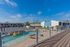 Inviting apartment complex with a sparkling outdoor pool and cozy sunbathing area, perfect for relaxation under a clear blue sky.