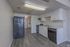 Sleek modern kitchen featuring white cabinetry, stainless steel appliances, and wood flooring, leading to a convenient in-unit laundry area.