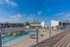 Vibrant poolside view of a modern apartment complex with clear blue skies, featuring stylish railings and relaxing lounge chairs.