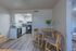 Inviting apartment kitchen with modern white cabinetry, sleek appliances, and an elegant wooden dining set, perfect for cozy dining experiences.