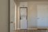 Modern laundry area with a sleek stackable washer and dryer in a bright, closet space with wood flooring.
