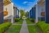 Charming apartment complex with lush green landscaping, modern architecture, and inviting walkways under a clear blue sky.