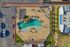Aerial view of a relaxing outdoor area featuring a resort-style pool surrounded by stylish loungers and greenery, perfect for leisurely afternoons.