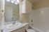 Bright and inviting bathroom featuring a sleek granite countertop, modern vanity, and a spacious bathtub with elegant tile surround.