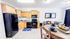 Charming open-plan kitchen and dining area with natural wood cabinets, sleek black appliances, and cozy seating perfect for family gatherings.