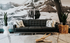 Chic living room with modern black sofa, unique wood accents, and striking mountain-themed mural.