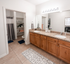 Elegant bathroom featuring dual sinks with granite countertops, wooden cabinetry, and a spacious layout including a shower area.