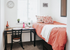 Cozy bedroom with vibrant orange bedding, a stylish desk, and ample natural light from a large window.