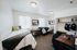 Bright and modern shared bedroom with two cozy beds, ample natural light, functional desk area, and chic open shelving.