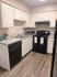 Modern kitchen with sleek black appliances, spacious countertops, and elegant white cabinetry for a refined cooking experience.