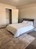 Cozy bedroom featuring a stylish gray bed, soft white bedding, and an inviting open closet on elegant hardwood flooring.