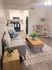 Chic open-plan living room with cozy gray sofa, modern kitchen, and elegant dining area, perfect for stylish urban living.
