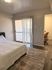 Bright and cozy bedroom with modern decor, featuring a plush bed, private balcony access, and a stylish workspace.