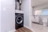 Contemporary bathroom with integrated laundry space, featuring a sleek washing machine and minimalistic design.