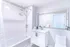 Bright modern bathroom with sleek fixtures, a bathtub, and a large mirror.