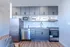 Contemporary kitchen with stainless steel appliances, wood flooring, and minimalist cabinetry.