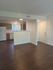 Inviting apartment interior featuring modern kitchen with wooden cabinets and expansive hardwood floors.