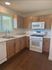Modern kitchen with wooden cabinets, pristine white countertops, and sleek appliances, offering a warm and inviting atmosphere.