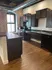 Chic urban kitchen with exposed brick, sleek dark cabinetry, and modern appliances.