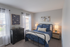 Cozy and inviting bedroom with modern decor, featuring a plush bed, elegant lamps, and natural light from large windows.