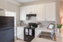 Bright and modern kitchen with sleek black appliances, stylish white cabinetry, and ample natural light.