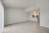 Bright, open-plan living area with stylish light wood flooring, seamlessly connected to a modern kitchen featuring sleek white cabinetry and stainless steel appliances.