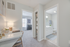Inviting hallway with a stylish workspace leading to a cozy bedroom and bright bathroom, showcasing modern design and ample natural light.
