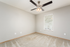 Bright and inviting bedroom with soft carpeting, modern ceiling fan, and a sunlit window offering a serene atmosphere.