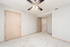 Bright and modern bedroom with plush carpet, neutral walls, and elegant ceiling fan in a chic apartment.