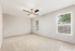 Bright and spacious bedroom with plush carpeting, modern ceiling fan, and large windows offering natural light and outdoor views.