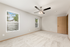 Bright and airy empty room featuring fresh carpeting, a sleek ceiling fan, and large windows with abundant natural light.