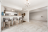 Inviting open-concept kitchen with stylish bar seating and modern lighting, leading into a spacious, carpeted living area.