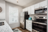 Modern kitchen with sleek stainless steel appliances, elegant granite countertops, and chic white cabinetry, bathed in natural light from a large window.