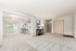Bright and spacious living room featuring plush carpet, an elegant dining area with chandelier, and a stylish breakfast bar with modern stools.