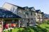 Charming townhouse exterior with a modern brick finish, featuring private patios with red chairs, perfect for relaxing amid lush green landscaping.