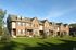 Charming row of brick townhouses with manicured lawns and bright blue sky, perfect for family living.