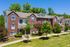 Charming red brick townhouses with picturesque windows and lush greenery in a tranquil suburban setting.