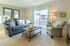 Bright and cozy living room featuring elegant seating, a rustic coffee table, and a large sliding glass door opening to a charming balcony view.