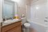 Modern bathroom featuring a sleek granite countertop, elegant sink, and spacious bathtub.