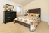 Inviting bedroom with plush carpeting, vibrant bedding, sleek dark dresser, and a large window offering natural light.