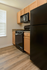 Elegant kitchen with modern black appliances, sleek wooden cabinets, and beautiful hardwood floors, bathed in natural light.