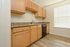 Spacious kitchen with sleek wooden cabinets, modern countertops, and ample natural light through a large window.