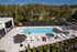 Luxurious outdoor pool area with modern lounge chairs and umbrellas, surrounded by lush greenery, perfect for relaxation and summer enjoyment.
