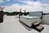 Luxurious rooftop terrace featuring a modern hot tub, elegant sun loungers, and lush greenery under a vibrant sky.