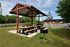 Charming outdoor picnic area with a covered seating space and a barbecue grill, surrounded by lush greenery, ideal for gatherings.