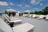 Elegant rooftop terrace with modern lounge chairs and parasols, offering a serene outdoor relaxation space with lush greenery and open skies.