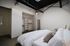 Modern bedroom with skylight, white bedding, and spacious walk-in closet for an airy and inviting atmosphere.