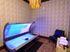 Luxurious room featuring a modern tanning bed with glowing lights, plush seating, elegant patterned walls, and a stylish chandelier.