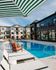 Luxurious poolside view showcasing modern apartment complex with elegant architecture and inviting lounge chairs under striped umbrellas.